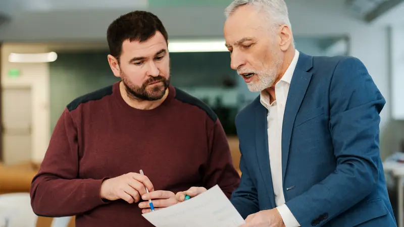 Two men standing in an office, going over a printed report together