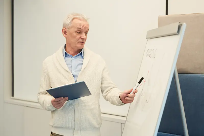 A man holding a clipboard and pointing to notes on a flip chart